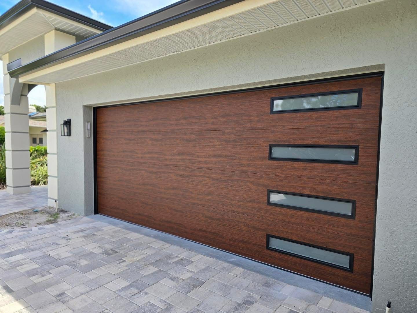 A wooden garage door with a brick driveway in front of a house.