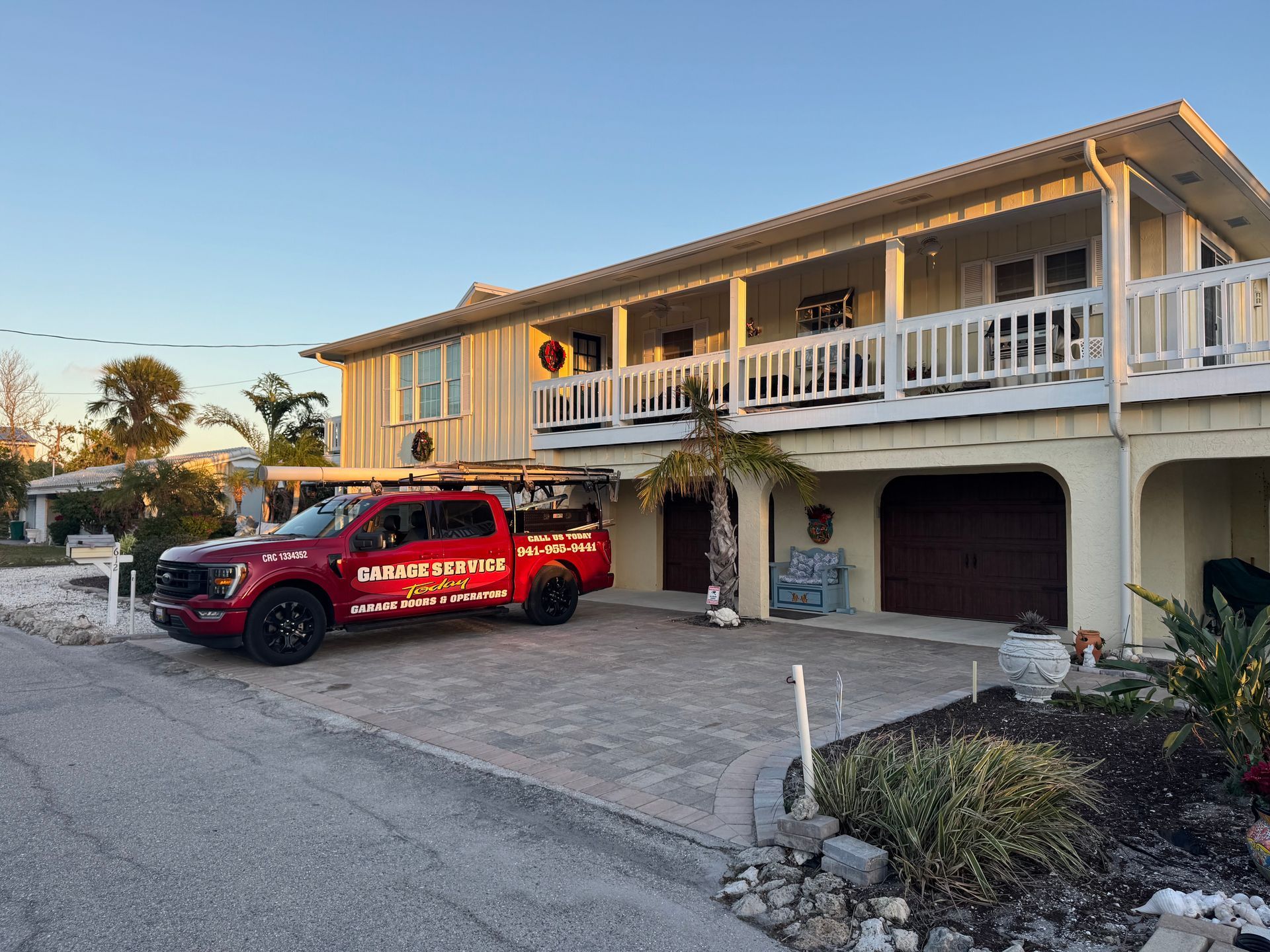 Red moving truck parked in a driveway beside a two-story house at sunset.