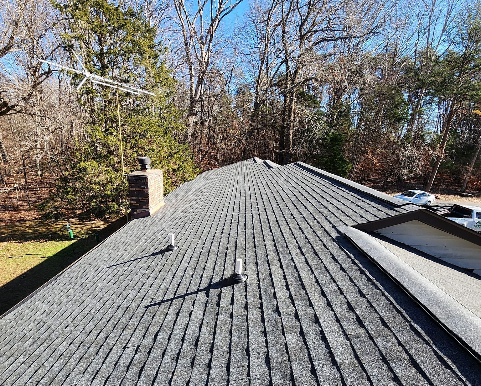 The roof of a house with a chimney and a satellite dish on it.