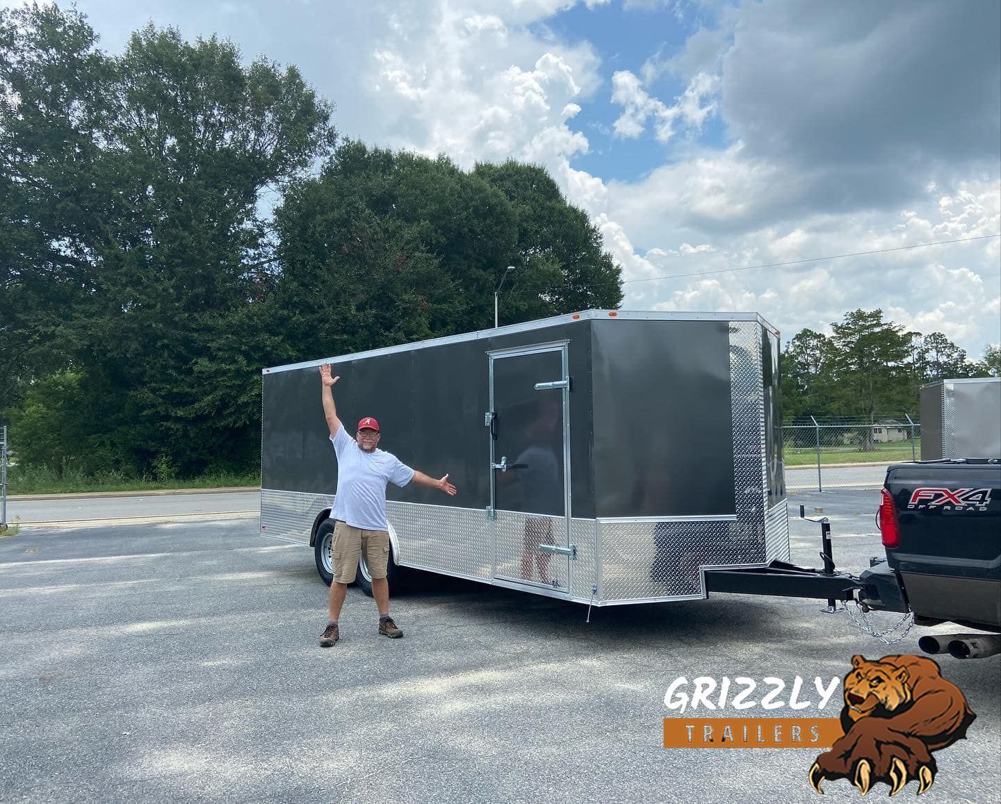 A man is standing next to a trailer in a parking lot.