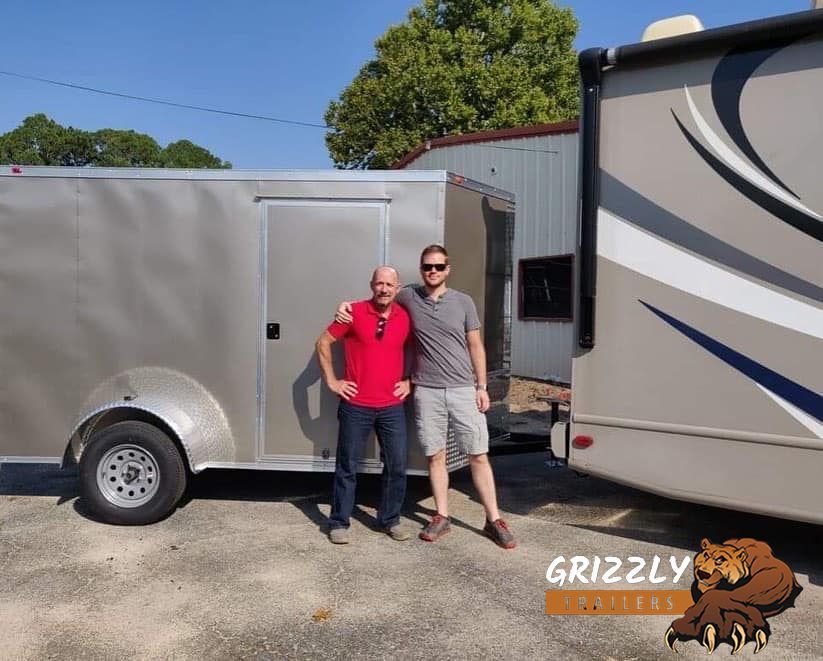 A truck is pulling a blue trailer in a parking lot.