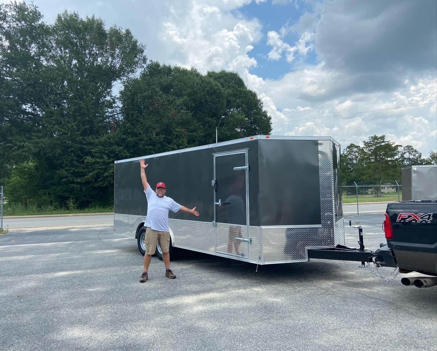 A man is standing next to a trailer in a parking lot.