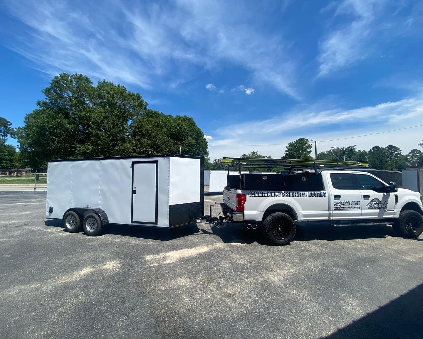 A white truck with a trailer attached to it is parked in a parking lot.