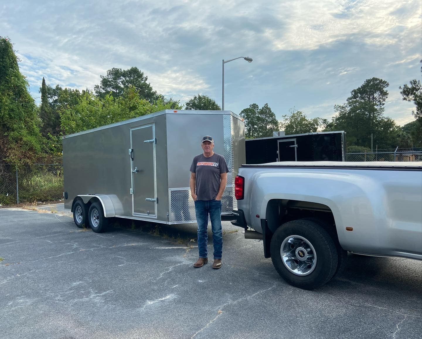 A man is standing next to a truck with a trailer attached to it.