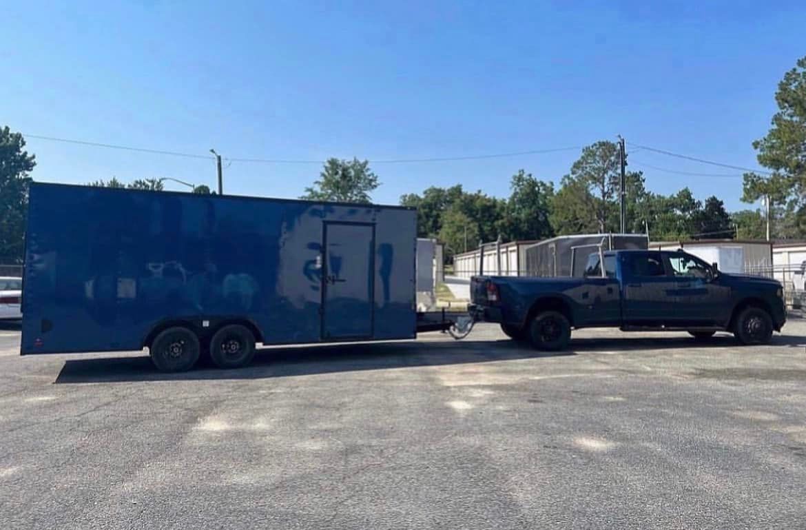 A truck is pulling a blue trailer in a parking lot.