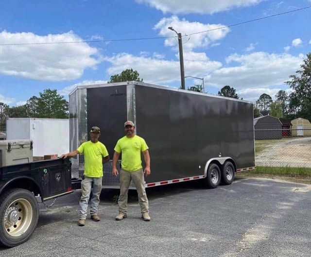 Two men standing next to a trailer in a parking lot