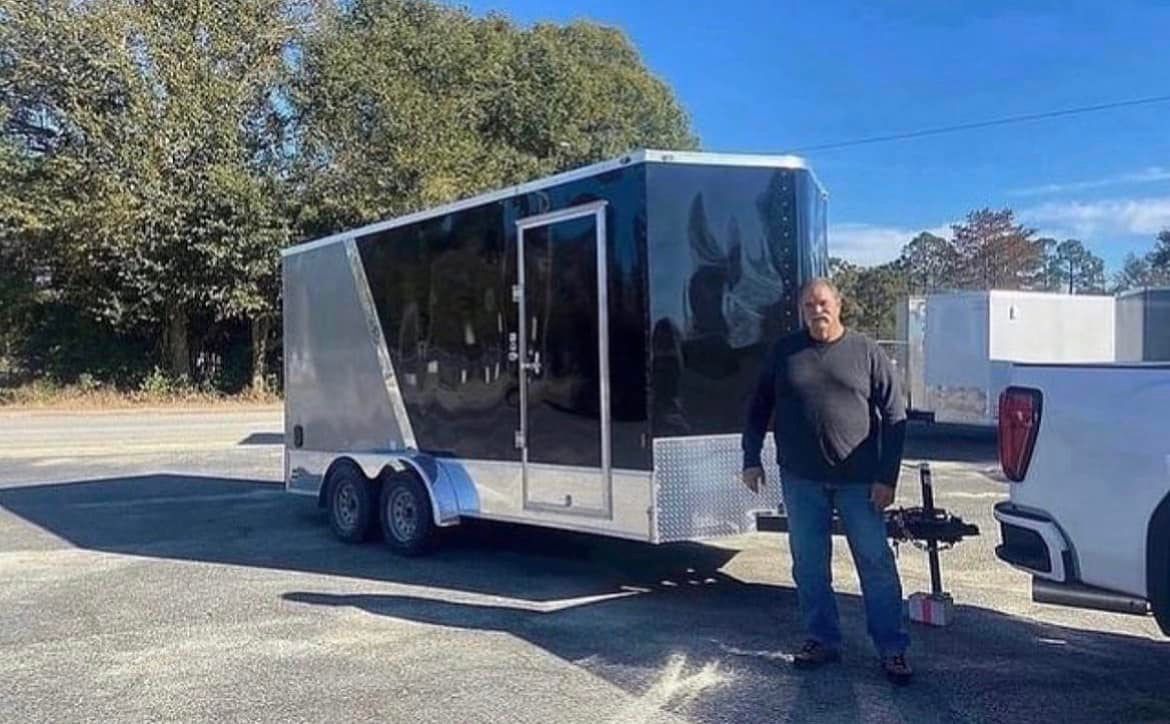A man is standing next to a trailer in a parking lot.