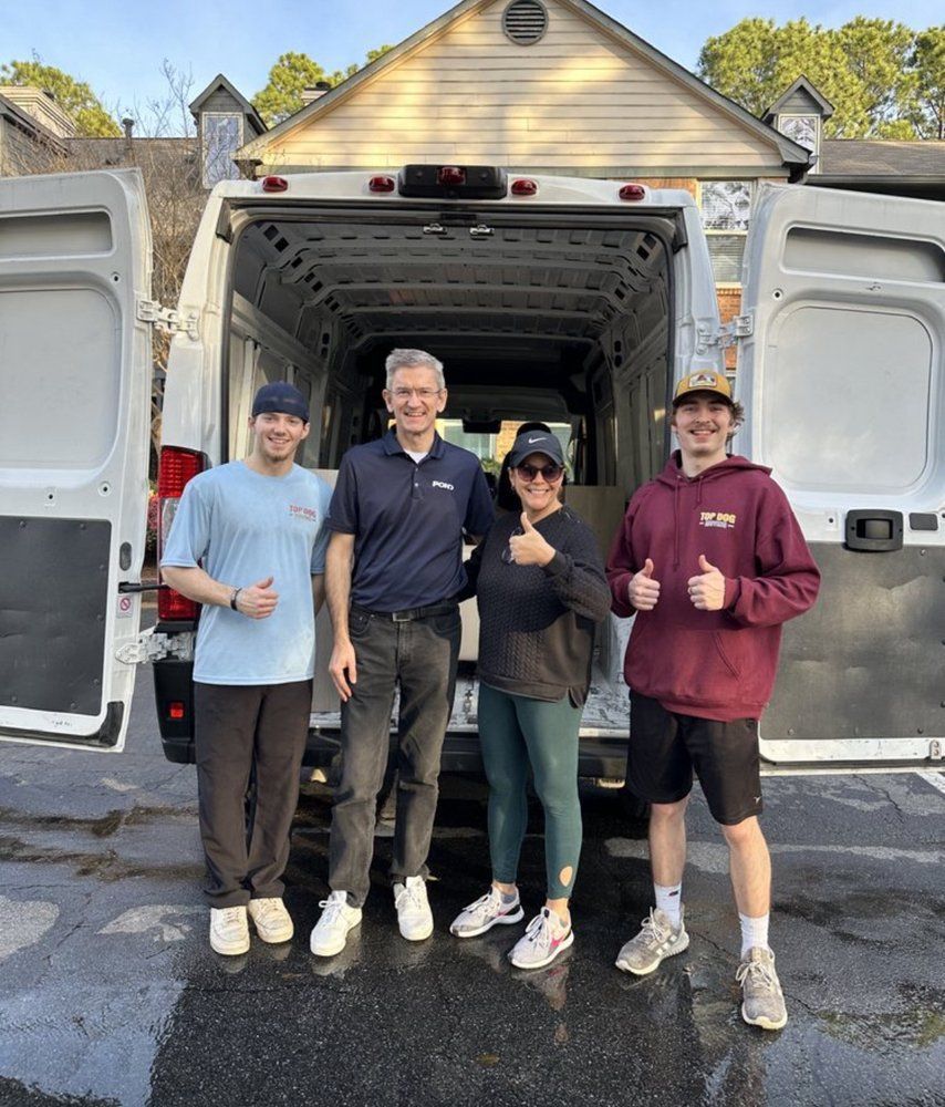 A group of people are standing in front of a van giving a thumbs up.