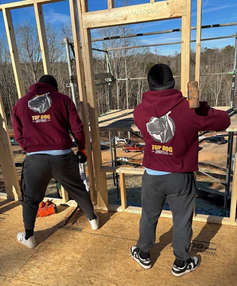Two men wearing top dog sweatshirts are working on a building