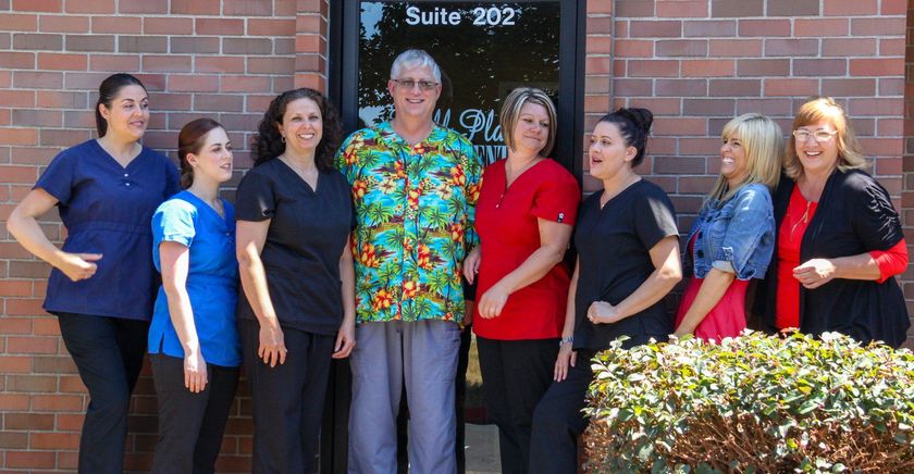 A group of people are posing for a picture in front of a building that says suite 202