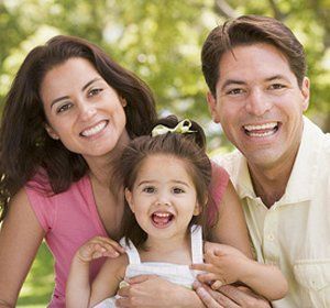 A man and woman are holding a little girl and smiling for the camera.