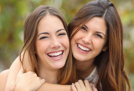 Two women are hugging each other and smiling for the camera.