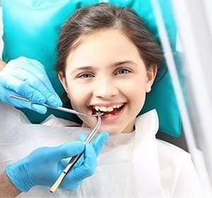 A young girl is having her teeth examined by a dentist.