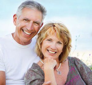 A man and a woman are smiling for the camera while sitting next to each other.