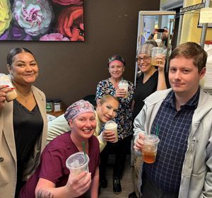 A group of people are standing next to each other holding cups of drinks.