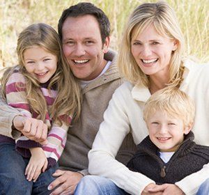 A family is posing for a picture while sitting in the grass.