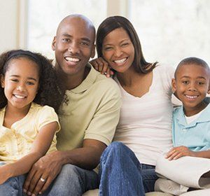 A family is posing for a picture while sitting on a couch.