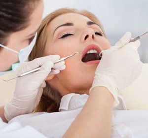 A woman is getting her teeth examined by a dentist.