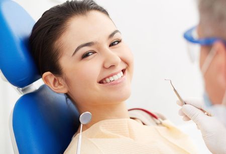 A woman is smiling while sitting in a dental chair.