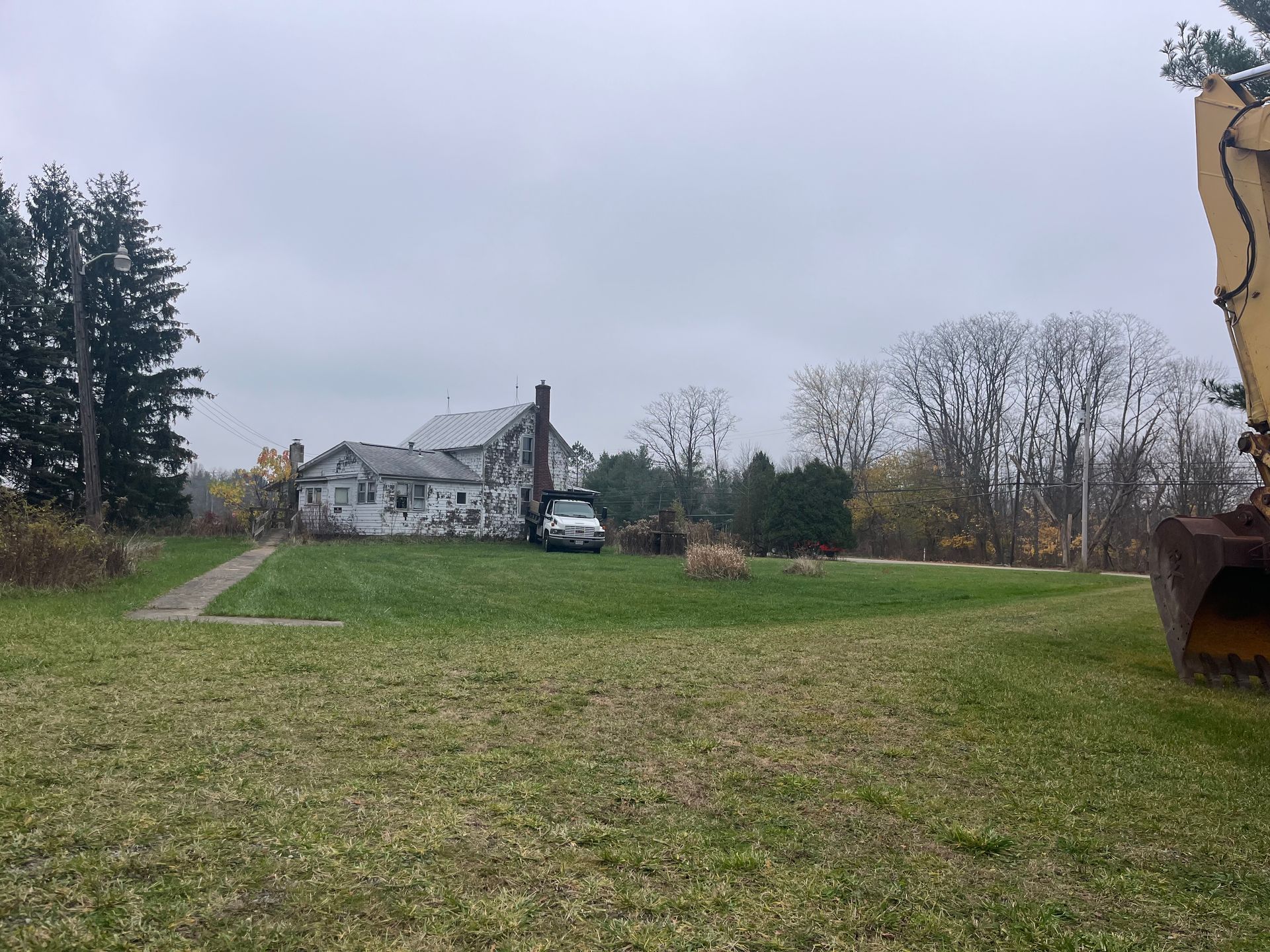 Old house with peeling paint on a grassy lawn; cloudy sky.