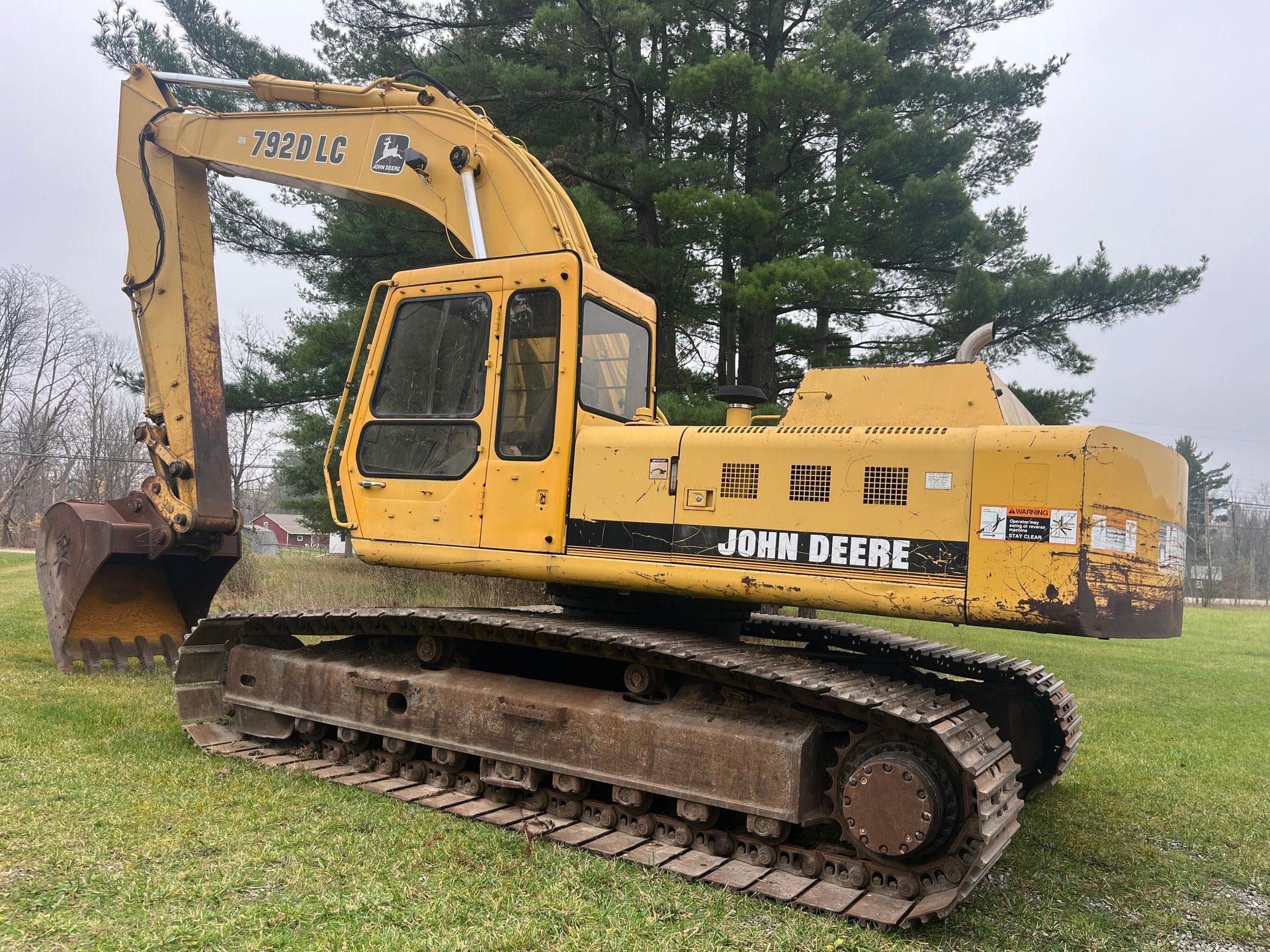 Yellow John Deere excavator on tracks in grassy area.