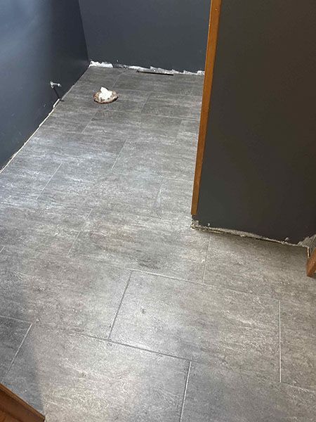 Grey tiled floor in a small room with dark grey walls, doorway, and a small object on the floor.