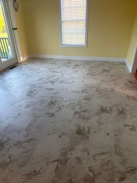 A room with light-colored marbled flooring, yellow walls, and a window with blinds.