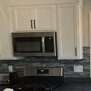 Kitchen with white cabinets, a stainless steel microwave, and black stovetop.