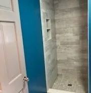 Bathroom with blue walls, grey tiled shower, and white door.