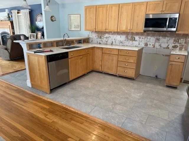 Kitchen with light wood cabinets, stainless steel appliances, and light gray tiled floor.