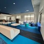 Modern lounge area with blue and white furniture, large windows, and blue ceiling.