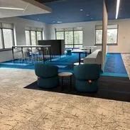 Modern office space with blue accents, seating, and a large table for collaboration.