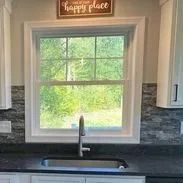 Kitchen sink under a window, countertop, cabinets, and a 