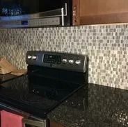 Kitchen: stove, countertop, mosaic backsplash, microwave. Dark colors dominate.