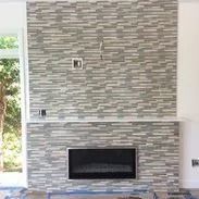 Fireplace with gray and white stacked tile, black firebox, and white mantel.