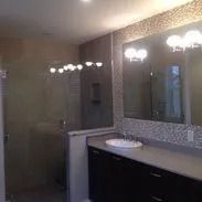 Bathroom with shower, dark vanity, large mirror, and neutral-toned tile.