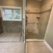 Bathroom with tiled shower, glass door, and pebble flooring.