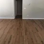 Wooden floor in a room with gray walls, hallway visible in the background.