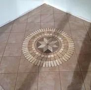Tan tiled floor with a decorative circular inlay featuring a starburst design.