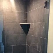 Gray tiled shower with a triangular shelf.