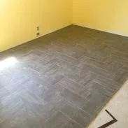 Herringbone pattern gray tile floor in a room with yellow walls.
