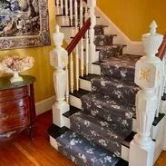 Wooden staircase with patterned runner, white balusters, and a wooden cabinet.