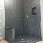 Dark gray tiled shower stall with a bench and a recessed shelf.