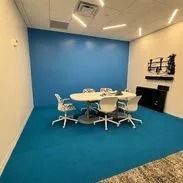 Blue meeting room with oval table, chairs, and blue carpet.