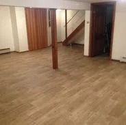 Empty room with wood-look flooring, wooden door and paneling, and a staircase.