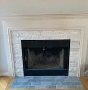 Fireplace with white mantle, gray-tiled surround, and dark interior with blue-gray tiled hearth.