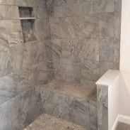 Gray marble tile shower with a built-in bench and shelf.