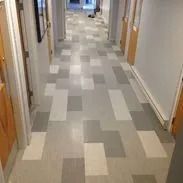 Hallway with gray, light gray, and white patterned floor tiles. Wooden doors line both sides.