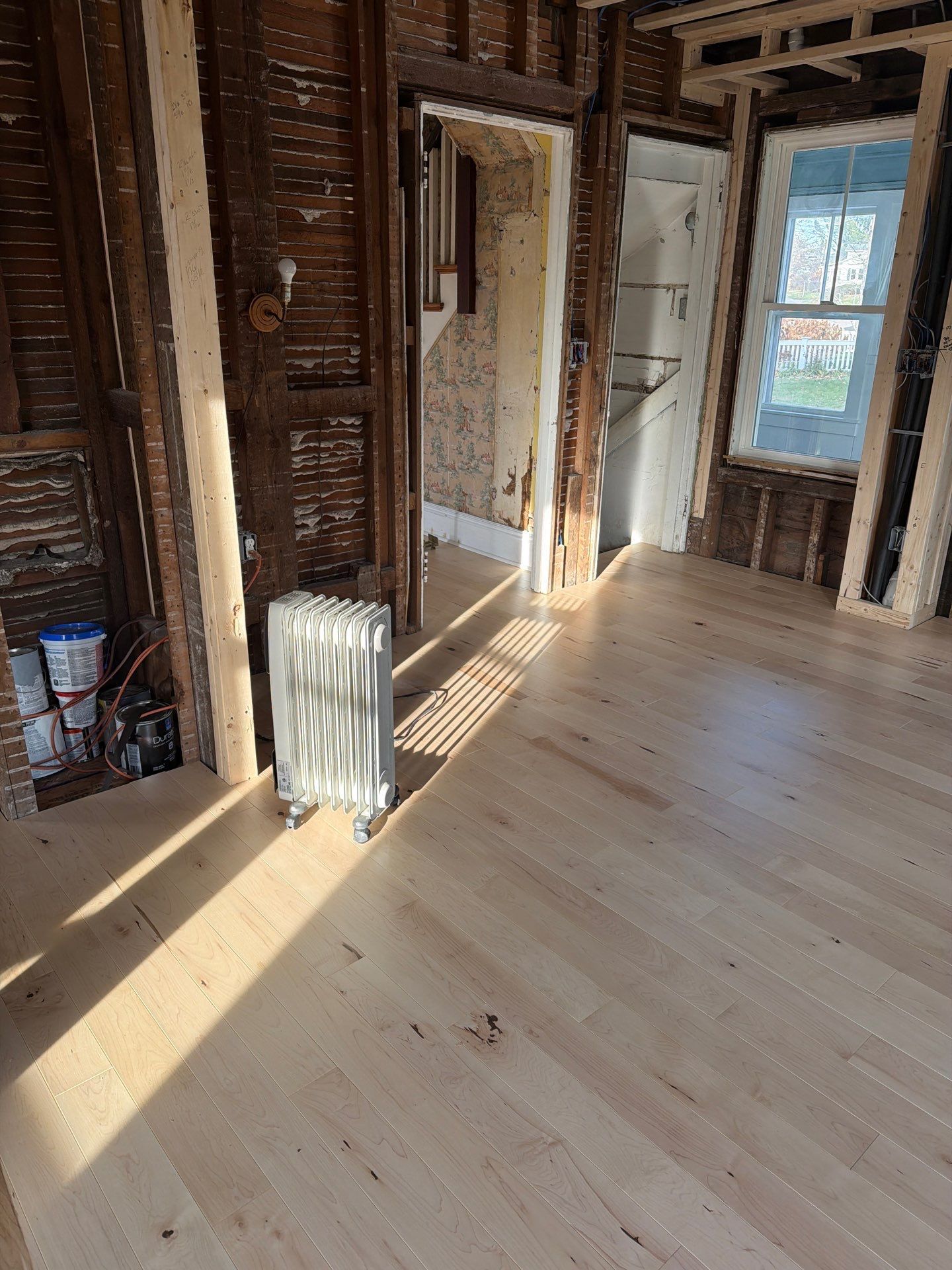 Room under renovation with new light-colored wood flooring.