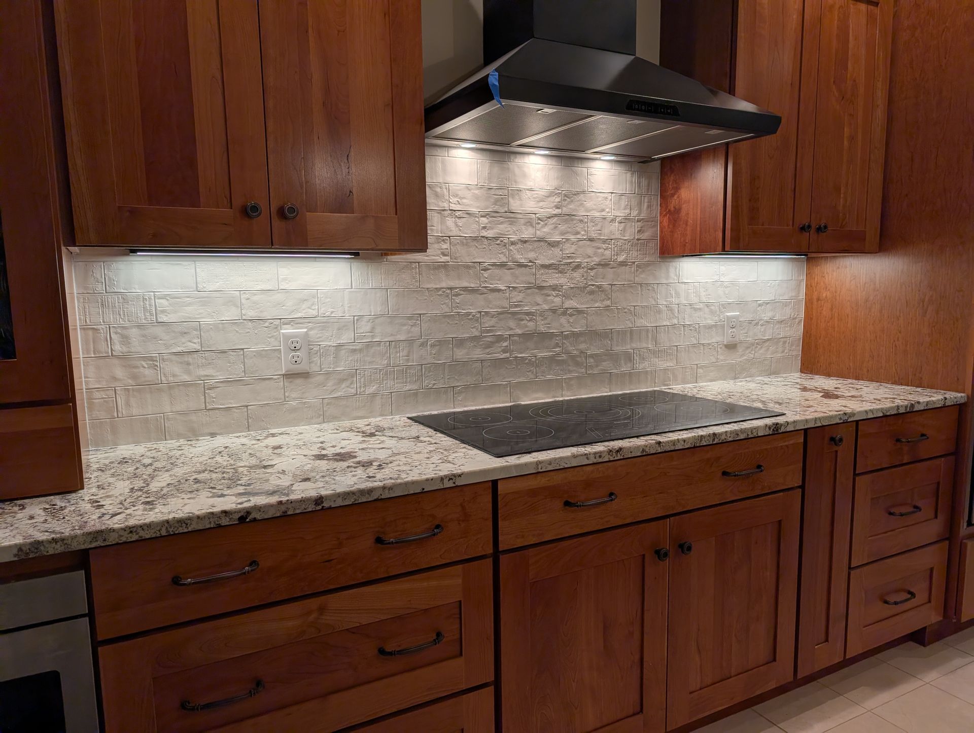 Kitchen with wood cabinets, stone countertops, and a white tile backsplash.